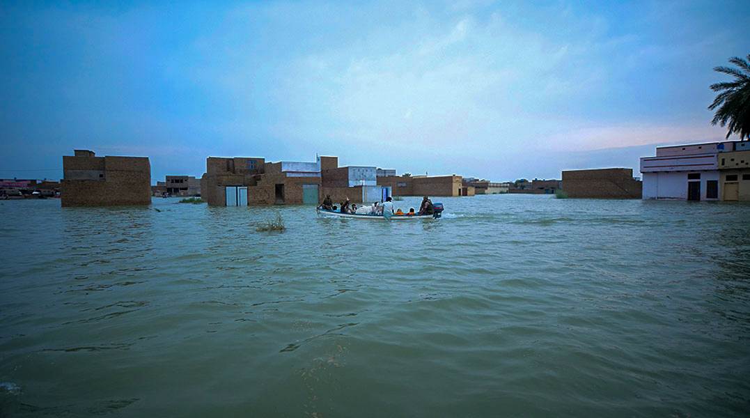 Floodwater submerges homes in a residential neighbourhood as a small rescue boat navigates between buildings