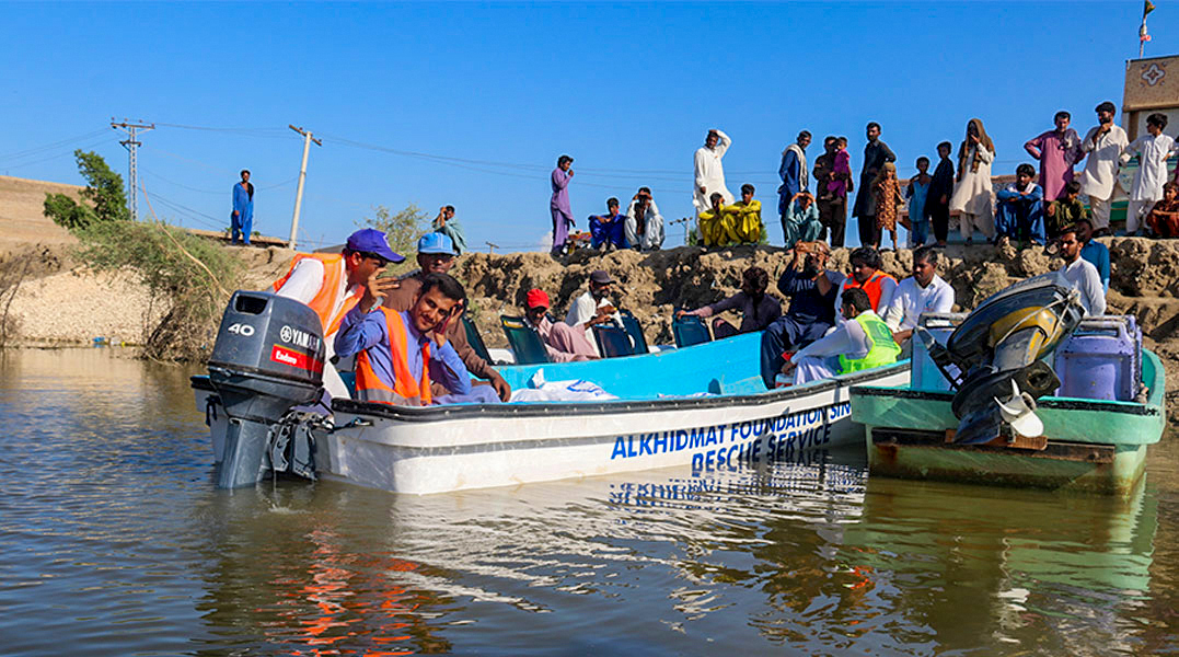 Alkhidmat Foundation volunteers in life jackets ferry stranded residents across floodwater in a rescue boat